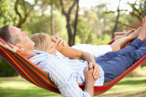 Senior couple relaxing together in a colorful hammock outdoors, smiling and enjoying a peaceful moment